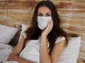 burning woman in a medical mask lies in bed and touches her face with her hand quarantine infection