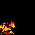 Burning wood at night, flame and fire sparks on dark abstract background, photo leaving place for imagination and meditations