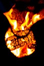 Burning wood and open flames seen through the cutout part of a metal fire pit Royalty Free Stock Photo