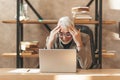 Burnout in the office. A depressed senior man sits at a laptop, holding his head. Misunderstanding and despair Royalty Free Stock Photo