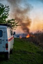 Burns dry grass, in sky smoke and soot.