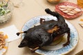 Burnt bird carcass on serving plate on dining table. Serve charred spoiled dish. Lousy housewife and bad chef. Delicious