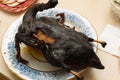 Burnt bird carcass on serving plate on dining table. Serve charred spoiled dish. Lousy housewife and bad chef. Overcook