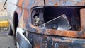 Burnt car body. Arson, short circuit. The skeleton of a burnt car. Front view of a burnt and abandoned rusty van and a