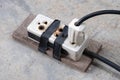 Burnt electrical socket and plug, poor quality product on the cement floor background Royalty Free Stock Photo