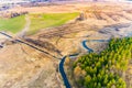 Burnt grass in field, aerial landscape. Narrow river flowing along small forest