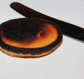 Burnt little pancake lies on a white surface with a knife