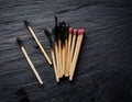 A burnt match lying next to unused matches on a slate surface, capturing exhaustion and setbacks Royalty Free Stock Photo