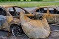 Burnt-out rusty cars on a city street, vandalism. Setting fire to cars by vandals and damage to property Royalty Free Stock Photo