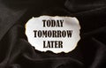 Burnt white piece of paper with text Today Tomorrow Later on a black fabric background Royalty Free Stock Photo