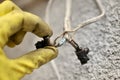 A man in a yellow glove holds a burnt wire closeup.