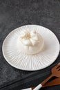 burrata on a beautiful handmade white plate. The dish is set against a dark background, copy space