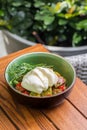 Burrata salad with cherry tomatoes, pesto and spices in a bowl
