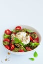 Burrata salad with cherry tomatoes, pesto and spices in bowl on white background