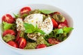 Burrata salad with cherry tomatoes, pesto and spices in bowl on white background