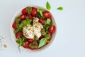 Burrata salad with cherry tomatoes, pesto and spices in bowl on white background