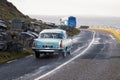 Burren, Ireland - 14.02.2022 - Old vintage car on a small asphalt road by the ocean and tourist bus