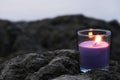 Burring aroma candle on rocks in the blurred background. Candle flame lights in glass. Royalty Free Stock Photo