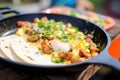 burrito in frying pan, eggs and sausage sizzling Royalty Free Stock Photo