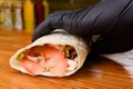 Burrito making process. The chef wraps stuffed pita on a wooden table. Mexican dish