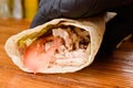 Burrito making process. The chef wraps stuffed pita on a wooden table. Mexican dish