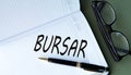 BURSAR - word in notebook on green background with glasses and pen Royalty Free Stock Photo