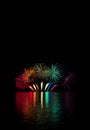 Burst of exploding fountains in the color of rainbow over surface of Brno`s Dam with reflection on the surface of lake