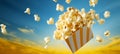 A burst of popcorn cascades from a striped container against a vibrant sunset backdrop Royalty Free Stock Photo
