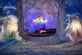 Burth of a Jesus installation inside of snow igloo house with colorful icy plafonds and burning candles