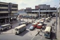 bus depot in busy city, with traffic and people bustling around