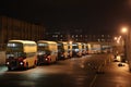 bus depot at night, with the lights shining and buses parked in rows