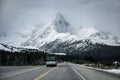 Bus driving on asphalt road with great snow mountain background Royalty Free Stock Photo