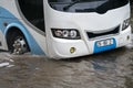 Bus splashes through a large puddle on a flooded street