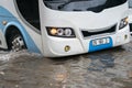 Bus splashes through a large puddle on a flooded street