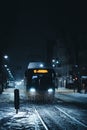 Bus traveling down a snow-covered road at night