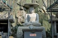 Ancient sitting Buddha wearing a hat image statue stone sculptures in Chinese culture located at Haedong Yonggungsa Temple in