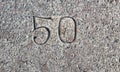 Bush-hammered rough limestone surface with carved number