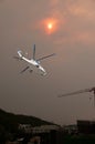 Bushfire sunset sky with an airborne helicopter in the foreground. Sun glow over Gosford city through wildfire smoke and haze. Royalty Free Stock Photo