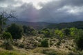 Bushland with black clouds and sun coming thru the clouds, shining on a dried out river bed Royalty Free Stock Photo
