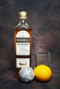 Bushmills whiskey bottle, branded whiskey glass, christmas tree ball and lemon on dark vintage background, copy space