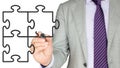 Businemman in a grey suit drawing three jigsaw pieces Royalty Free Stock Photo