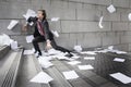 Busines man catching falling paperwork on steps