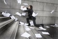 Busines man catching falling paperwork on steps