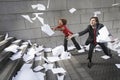 Busines man and woman catching falling paperwork on steps