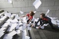 Busines man and woman catching falling paperwork on steps