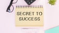 notepad with text SECRET TO SUCCESS. White background. Business
