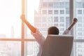 Business achievement concept with happy businessman relaxing at work in office room, resting and raising fists with ambition