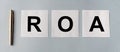 Business Acronym ROA, Return on assets. white papers with silver pen on blue table flatly, banner, top view