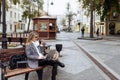 Business adult caucasian woman sitting with laptop and talking on speakerphone in city square Royalty Free Stock Photo