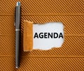 Business and agenda symbol. The concept word `agenda` appearing behind torn brown paper. Metallic pen. Beautiful brown backgroun Royalty Free Stock Photo